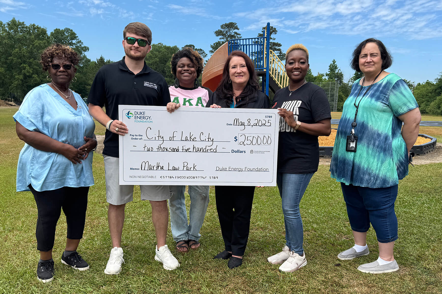 Six people hold a $2,500 Duke Energy Foundation check to Lake City for Martha Law Park.